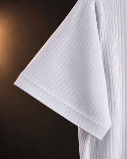 Detalle de la tela acanalada en la manga de la remera blanca