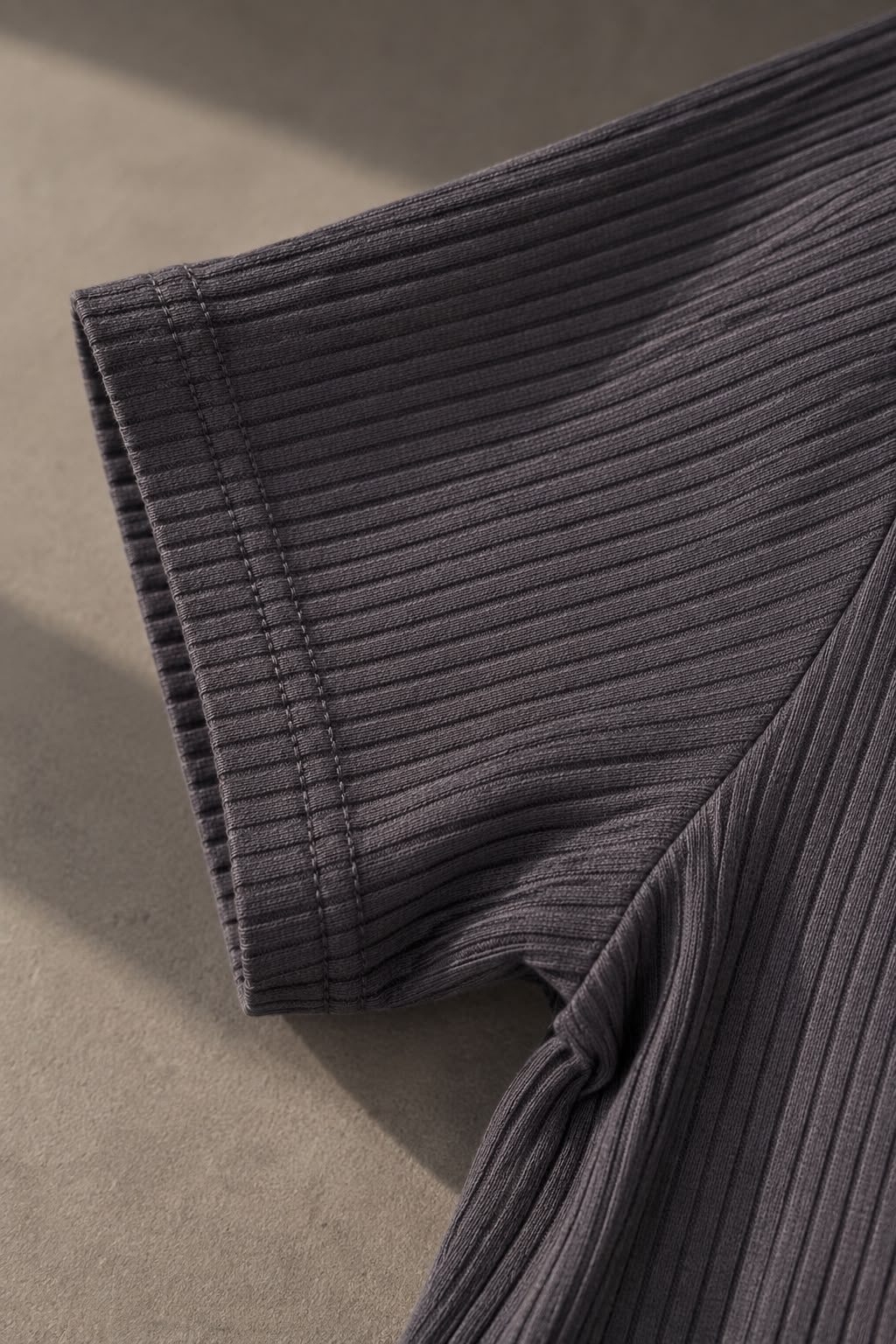 Detalle de la tela acanalada en la manga de la remera gris