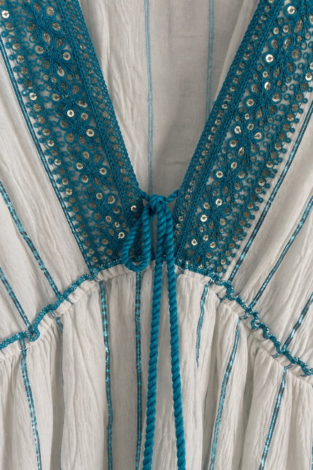 Detalle del escote en V bordado con lentejuelas del vestido celeste y blanco