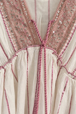 Detalle del escote en V bordado con lentejuelas del vestido rosa y blanco