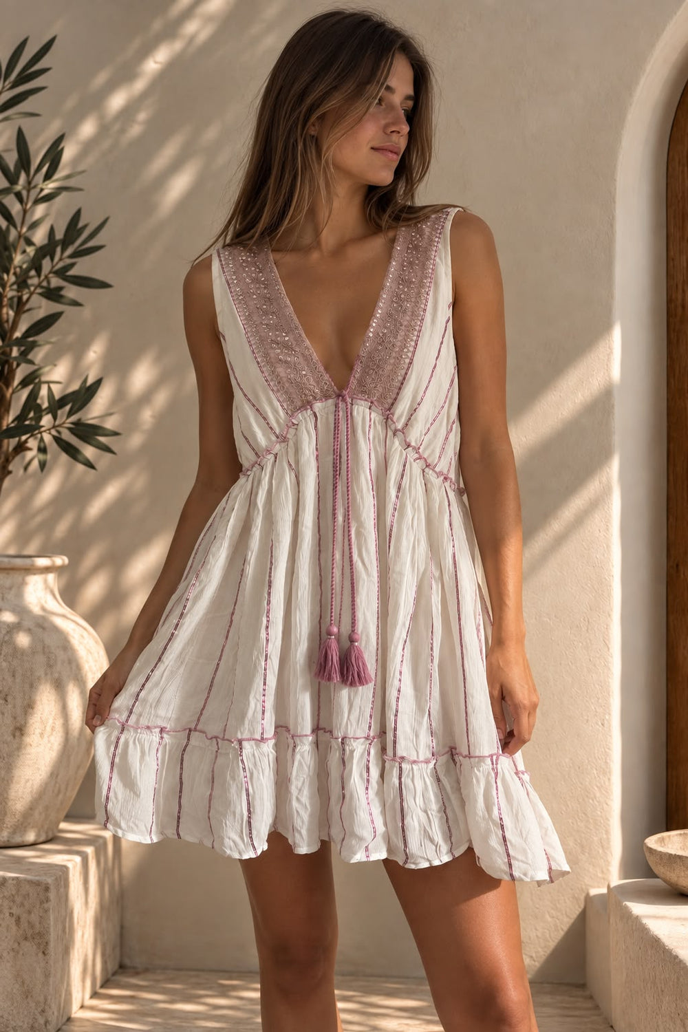 Mujer usando el vestido rosa y blanco sin mangas, con cordón y borlas en la cintura