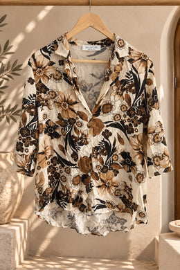 Camisa floreada de mujer con estampado de flores marrones y negras, colgada en percha
