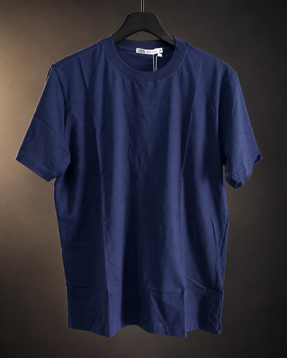 Remera básica azul de hombre, lisa y de cuello redondo, colgada en percha