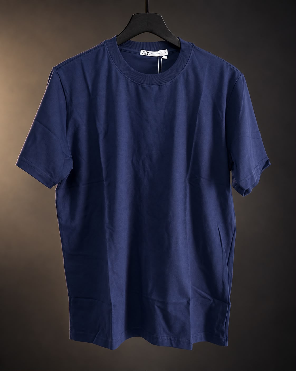 Remera básica azul de hombre, lisa y de cuello redondo, colgada en percha