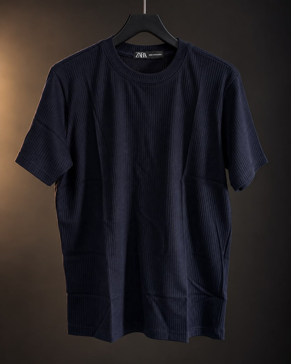 Remera acanalada azul de hombre colgada en percha