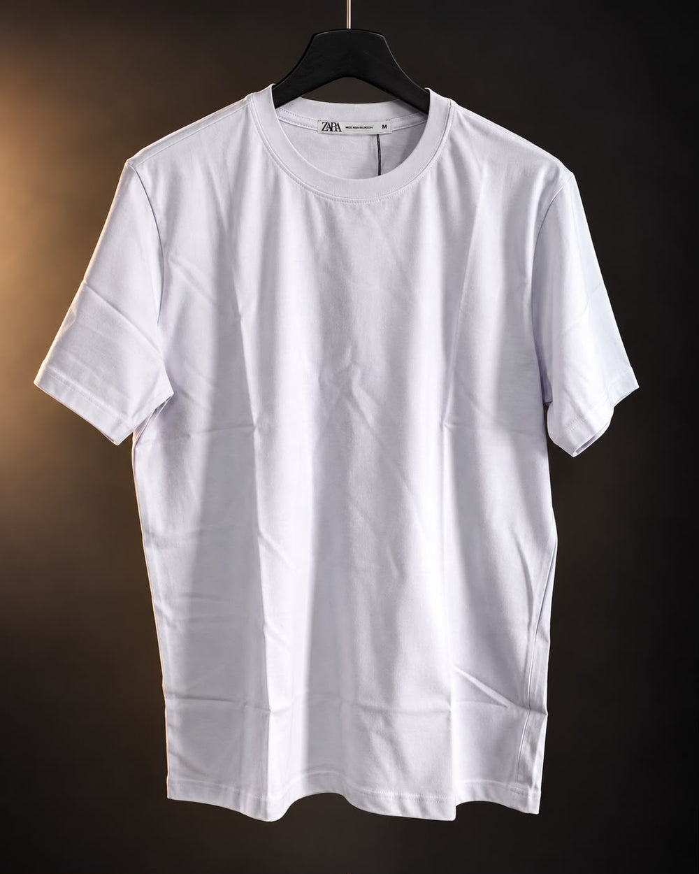 Remera básica blanca de hombre, lisa y de cuello redondo, colgada en percha