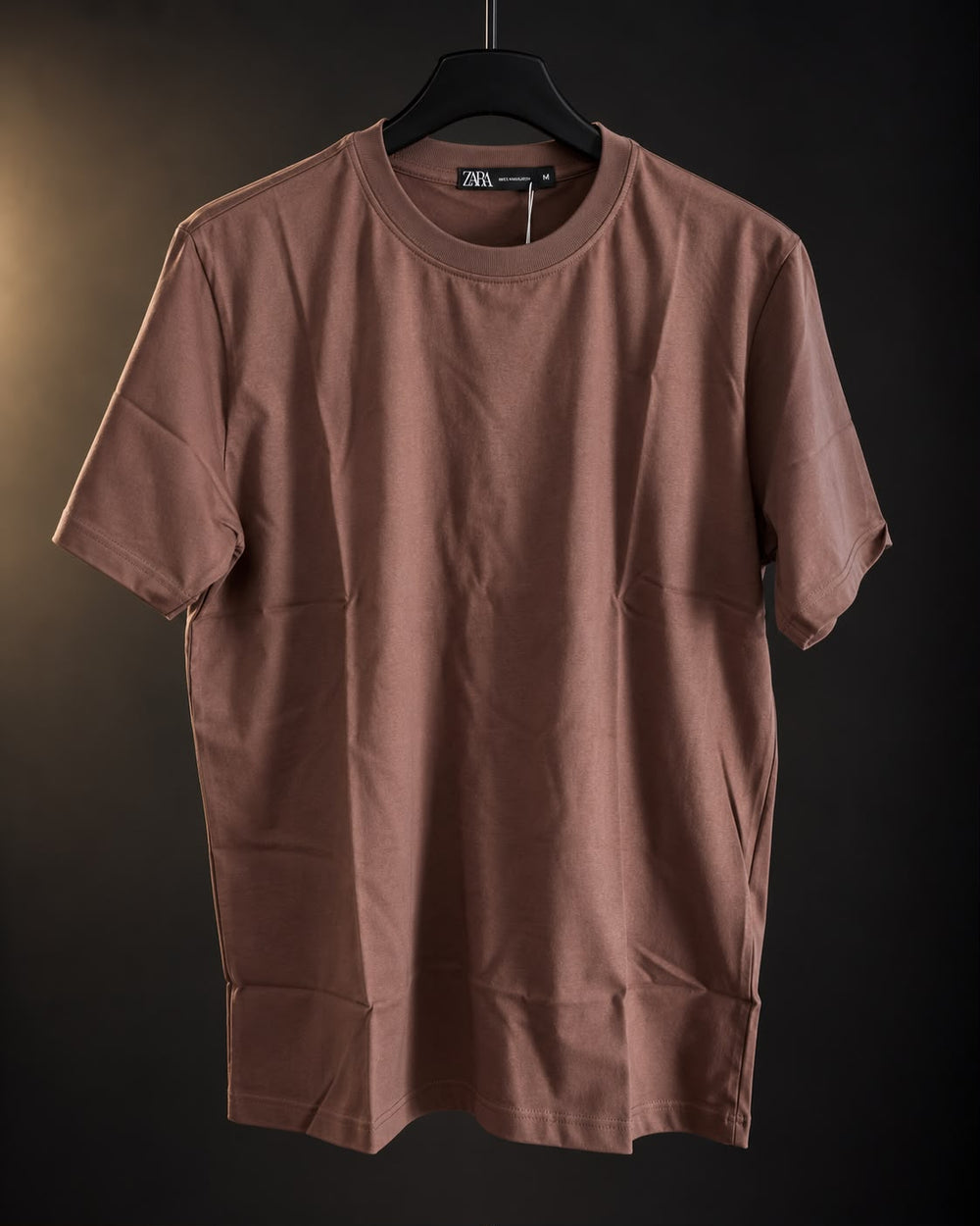 Remera básica marrón de hombre, lisa y de cuello redondo, colgada en percha