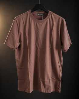 Remera básica marrón de hombre, lisa y de cuello redondo, colgada en percha