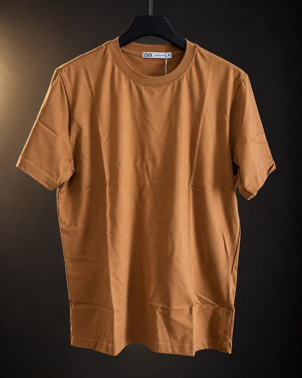 Remera básica mostaza de hombre, lisa y de cuello redondo, colgada en percha